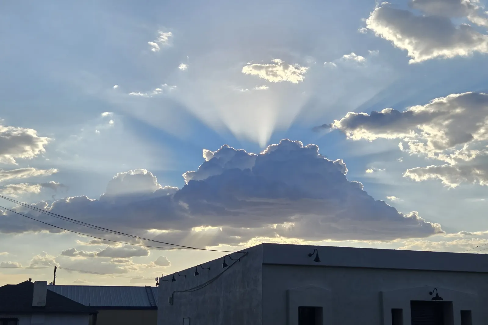 Sun rays breaking through storm clouds above rooftops in downtown Tucson, seen after a workout at the Lohse YMCA