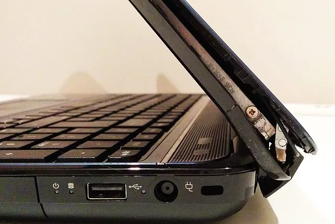 Laptop with a broken hinge is depicted.